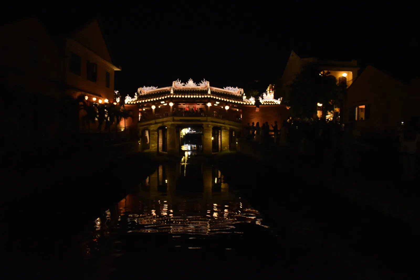 The illuminated Japanese Bridge reflected in the water in Hoi An
